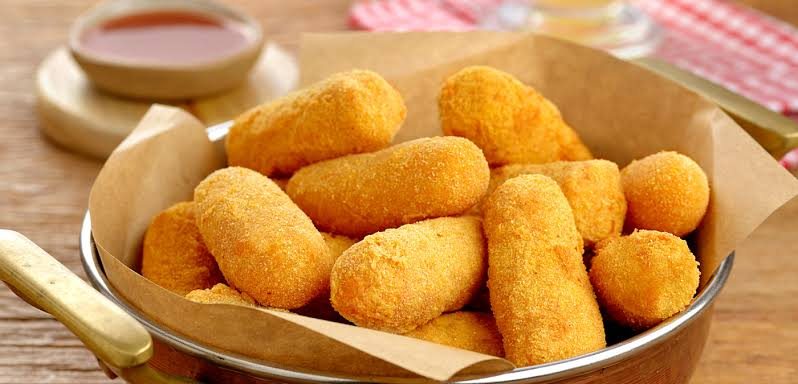 Croquetes de milho verde dourados em uma panela