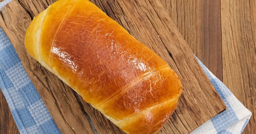 Pão caseiro dourado sobre tábua de madeira