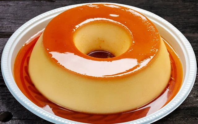 Pudim de leite sendo regado com calda de caramelo