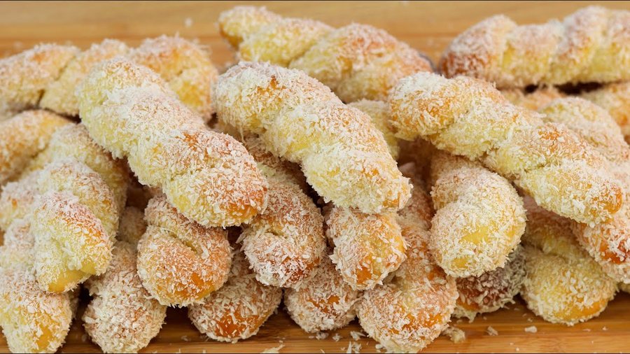 Rosquinhas de coco empilhadas, passadas na calda e no coco ralado